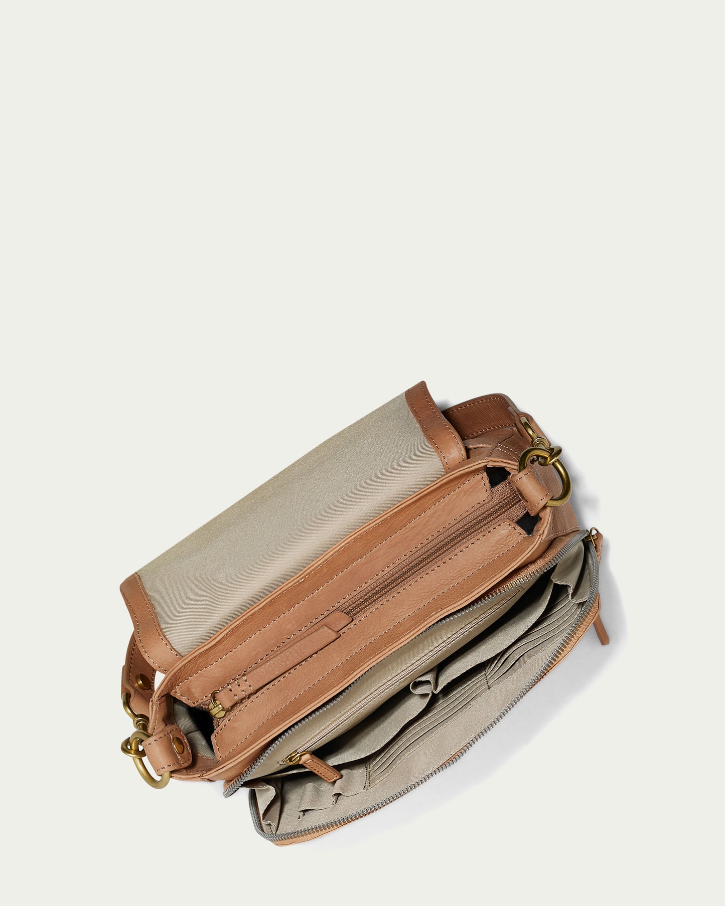 A top view of the American Leather Co. Marino Crossbody with 2 Straps in butter-soft leather. The beige and brown bag features multiple compartments, including zipped and open sections, with gold hardware accents against a simple, light-colored background.