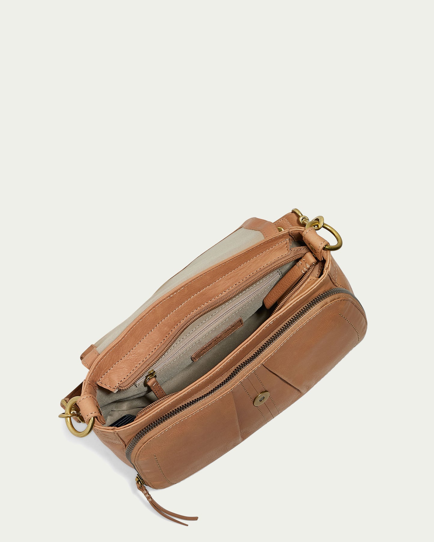 The Marino Crossbody with 2 Straps by American Leather Co., crafted from butter-soft leather, is shown open to reveal its beige interior and multiple compartments. Featuring gold-tone hardware, including a clasp and zipper pulls, it has a stitched pocket on the front. The bag’s removable strap adds versatility against a light background.