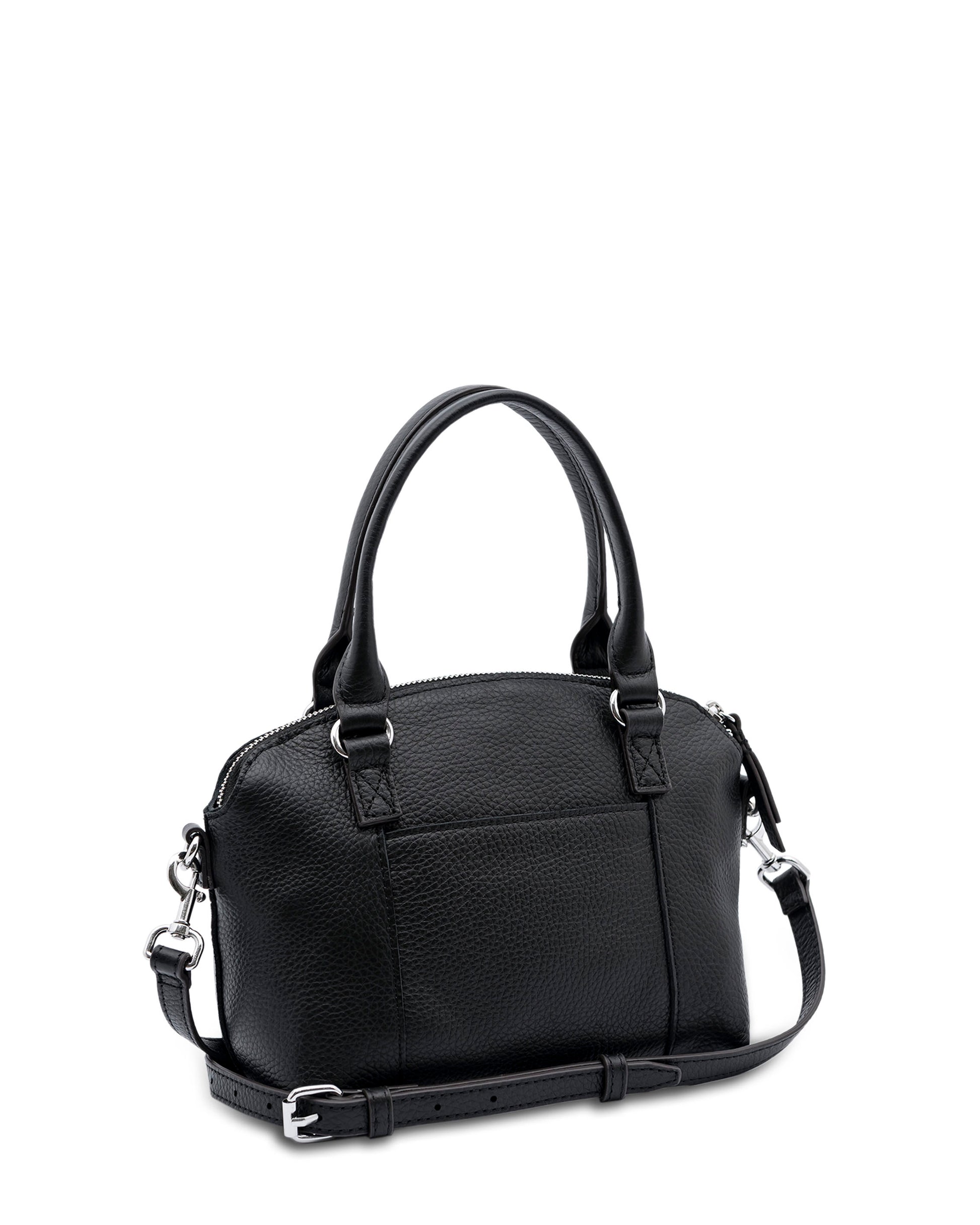 The Carrie Mini Dome Crossbody from American Leather Co. is a small black leather handbag featuring two short handles and a detachable, adjustable shoulder strap. This genuine leather bag showcases silver hardware and a zippered top closure, all designed with minimalist elegance.