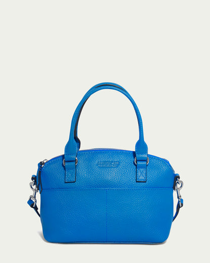 The Carrie Mini Dome Crossbody by American Leather Co. is a cerulean blue pebble leather handbag featuring two handles and a detachable shoulder strap. This genuine leather bag includes a zippered main compartment, multiple pockets for organized storage, and minimal stitching details around the handles and where the strap attaches.