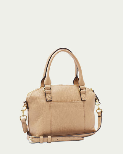 Introducing the Carrie Mini Dome Crossbody by American Leather Co., a small tan leather handbag boasting two handles and a detachable shoulder strap. This women's crossbody bag features gold-toned hardware, including buckles and clips, with a luxurious pebbled texture. It offers a top zipper closure and includes an exterior pocket on one side for added convenience.