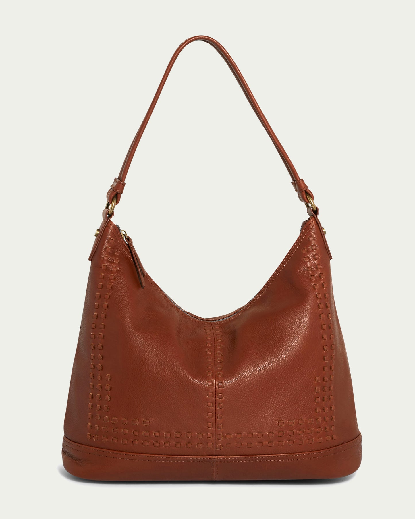 The Evelyn Hobo by American Leather Co. is a shoulder bag in a rich brandy color, boasting a simple, elegant design. Crafted from genuine American leather, it showcases square stitch detailing along the edges and features a single shoulder strap. With its soft, slightly curved shape, it suggests ample space and is perfect for everyday use.