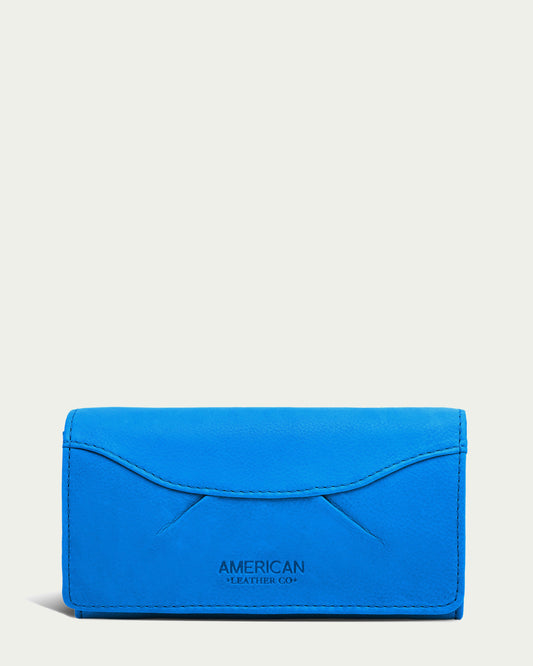 A cerulean blue genuine leather wallet with a smooth texture is displayed against a plain light background. The Hickory Bifold Wallet, by American Leather Co., features a flap closure with "AMERICAN LEATHER CO." embossed near the bottom center. The design is simple and elegant, offering maximized organization.