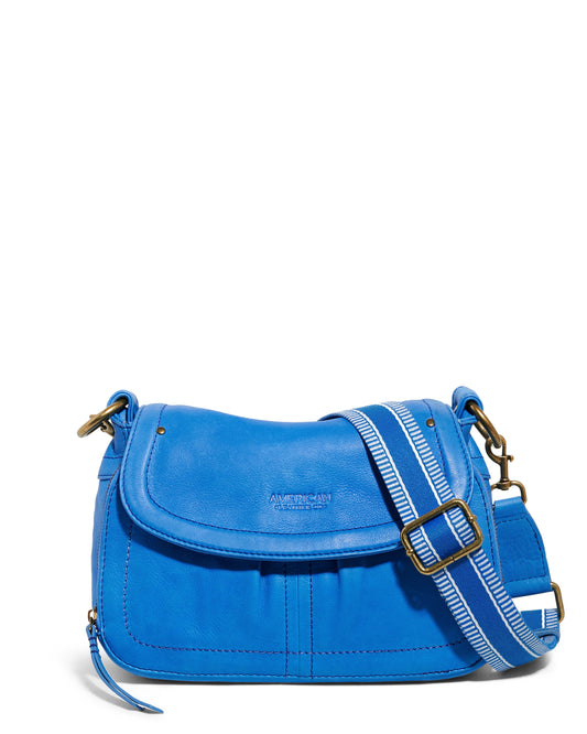 Introducing the Marino Crossbody with Built-In Wallet from American Leather Co. This vibrant blue handbag is crafted from genuine leather and features a secure flap closure. It comes with an adjustable striped shoulder strap for added versatility. The design includes brass hardware, such as buckles and clasps, along with a front pocket and an integrated wallet for enhanced convenience. The brand's logo is subtly embossed on the front of the flap, adding a touch of elegance to this stylish accessory.