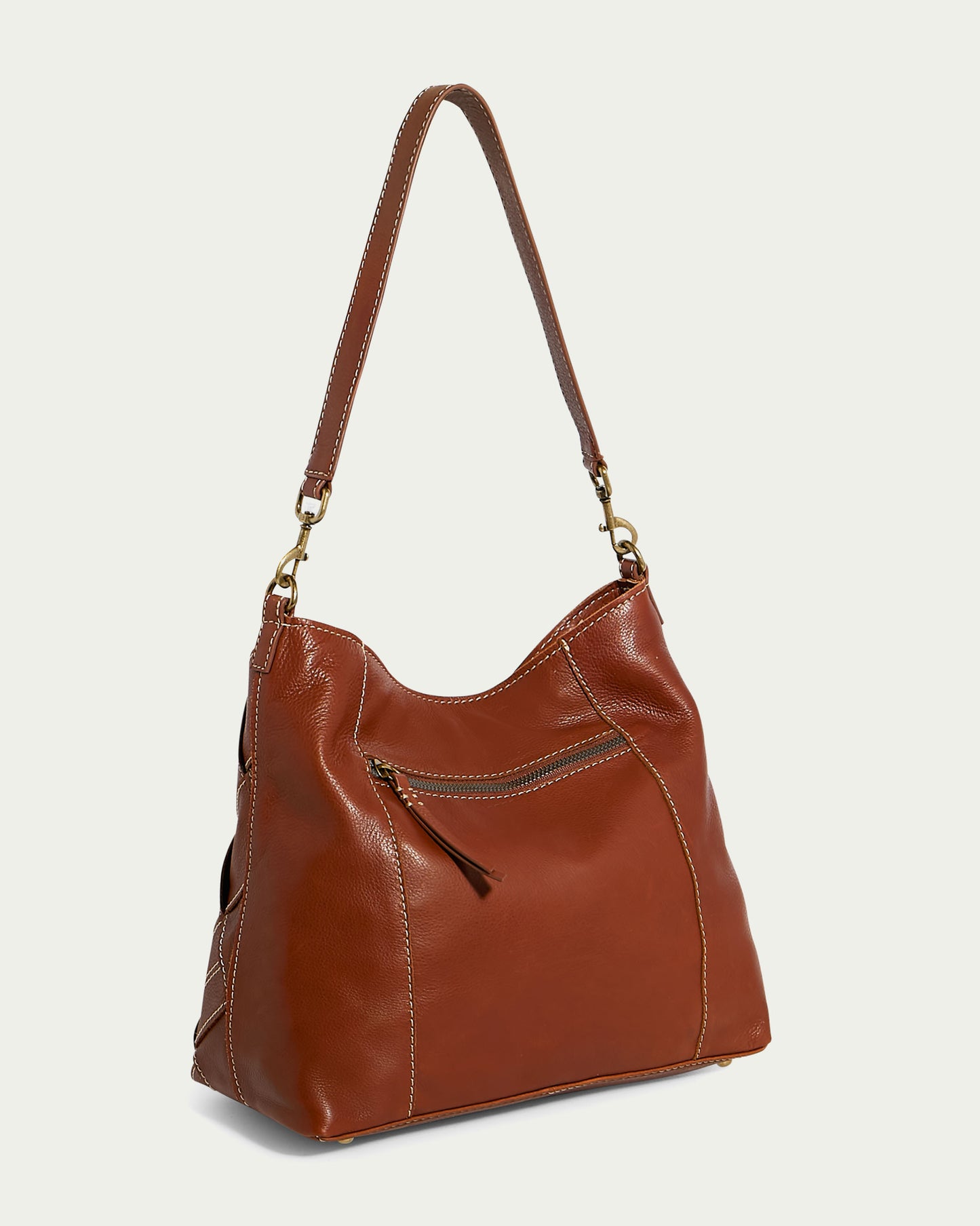 The Mercer Shoulder bag by American Leather Co. is a brown leather handbag with gold-tone hardware, featuring a long, detachable shoulder strap, a zippered front pocket, and decorative stitching. It showcases a slouchy, casual design with an accessible top opening and is crafted from genuine leather.