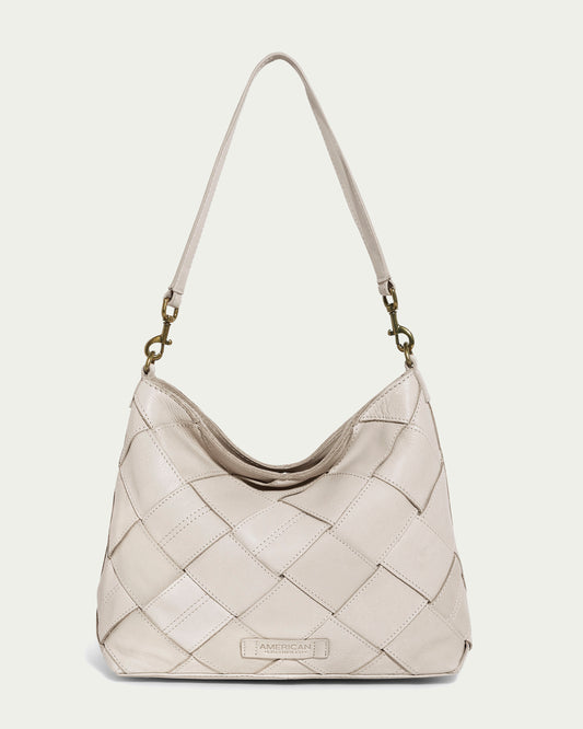 An ecru Mercer Shoulder bag by American Leather Co., featuring a quilted design with a single strap and brass hardware. Made from genuine leather, it has a subtle checkered pattern and a small embossed label at the bottom center, set against an off-white background.