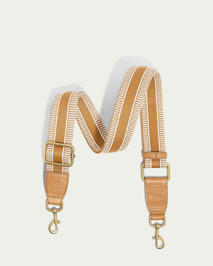 The Striped Web Strap from American Leather Co. is a detachable bag strap in a tan and white zigzag pattern featuring adjustable antiqued gold-tone hardware, displayed on a plain background.