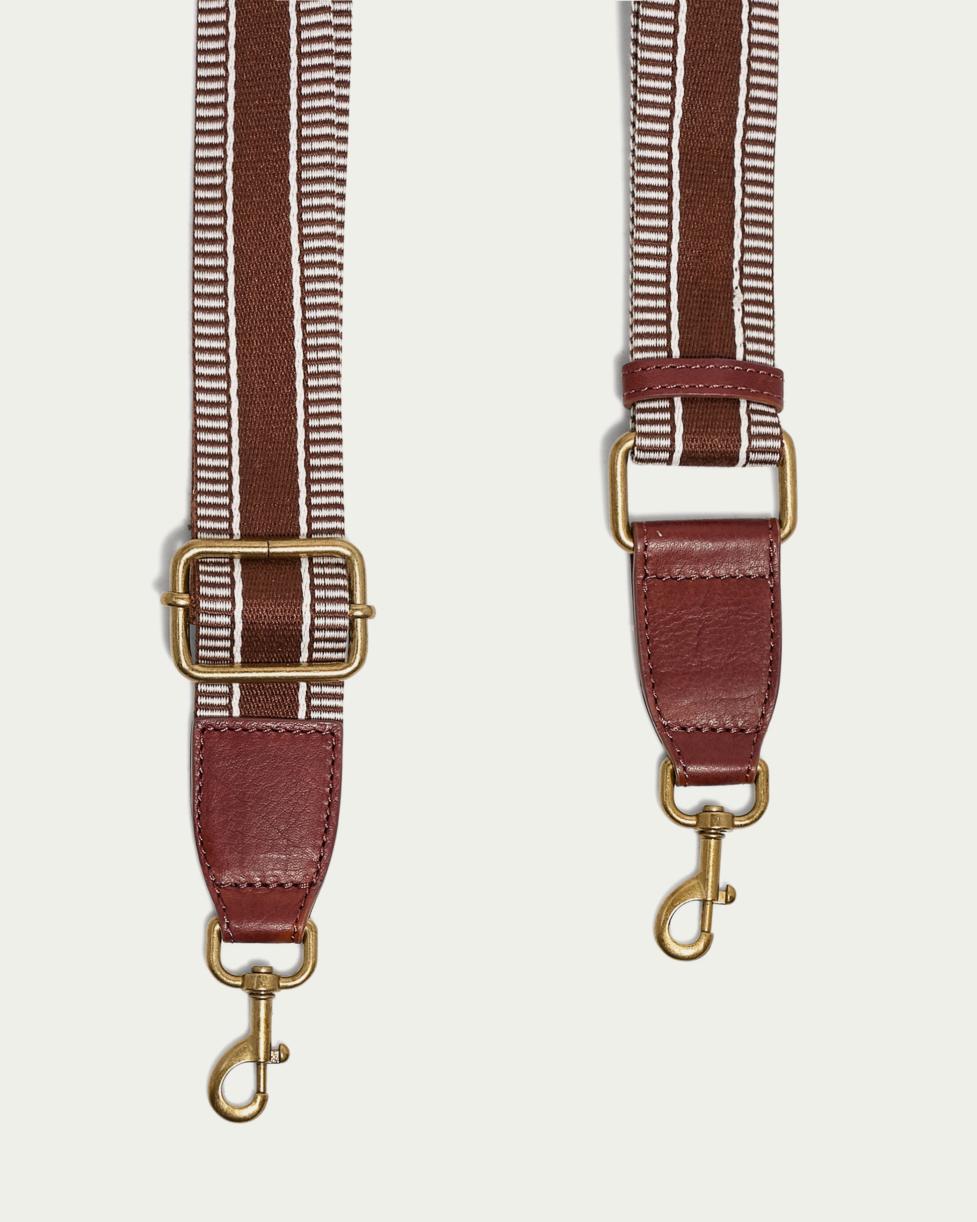 The Striped Web Strap by American Leather Co. includes a detachable design with brown and white woven stripes, adjustable gold-tone metal buckles, leather ends, and lobster clasp hooks for antiqued hardware that adds a classic touch.