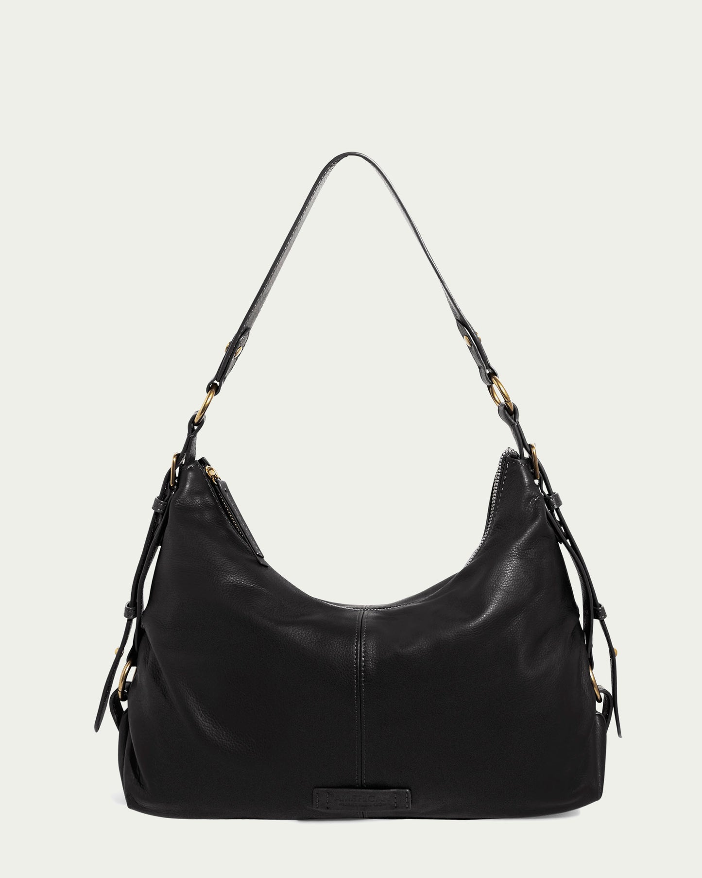 A sleek, black genuine leather shoulder bag with gold-tone hardware and adjustable straps from American Leather Co. The Thayer Perfect Hobo showcases a slouchy, crescent shape with a zip closure at the top and small side pockets. The background is plain and light-colored.