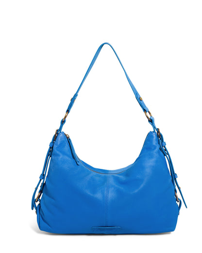 The American Leather Co. Thayer Perfect Hobo is a vibrant blue shoulder bag with a curved, slouchy shape, crafted from genuine leather. It features metal accents on the strap attachments and boasts a subtle stitched design on the front.