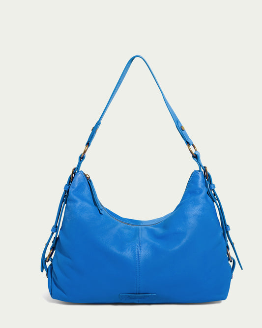 Introducing the Thayer Perfect Hobo by American Leather Co.: a vibrant blue masterpiece crafted from genuine leather. This handbag features an adjustable strap, gold-tone hardware, and elegant side tassels. Its sleek design stands out beautifully against a light background.