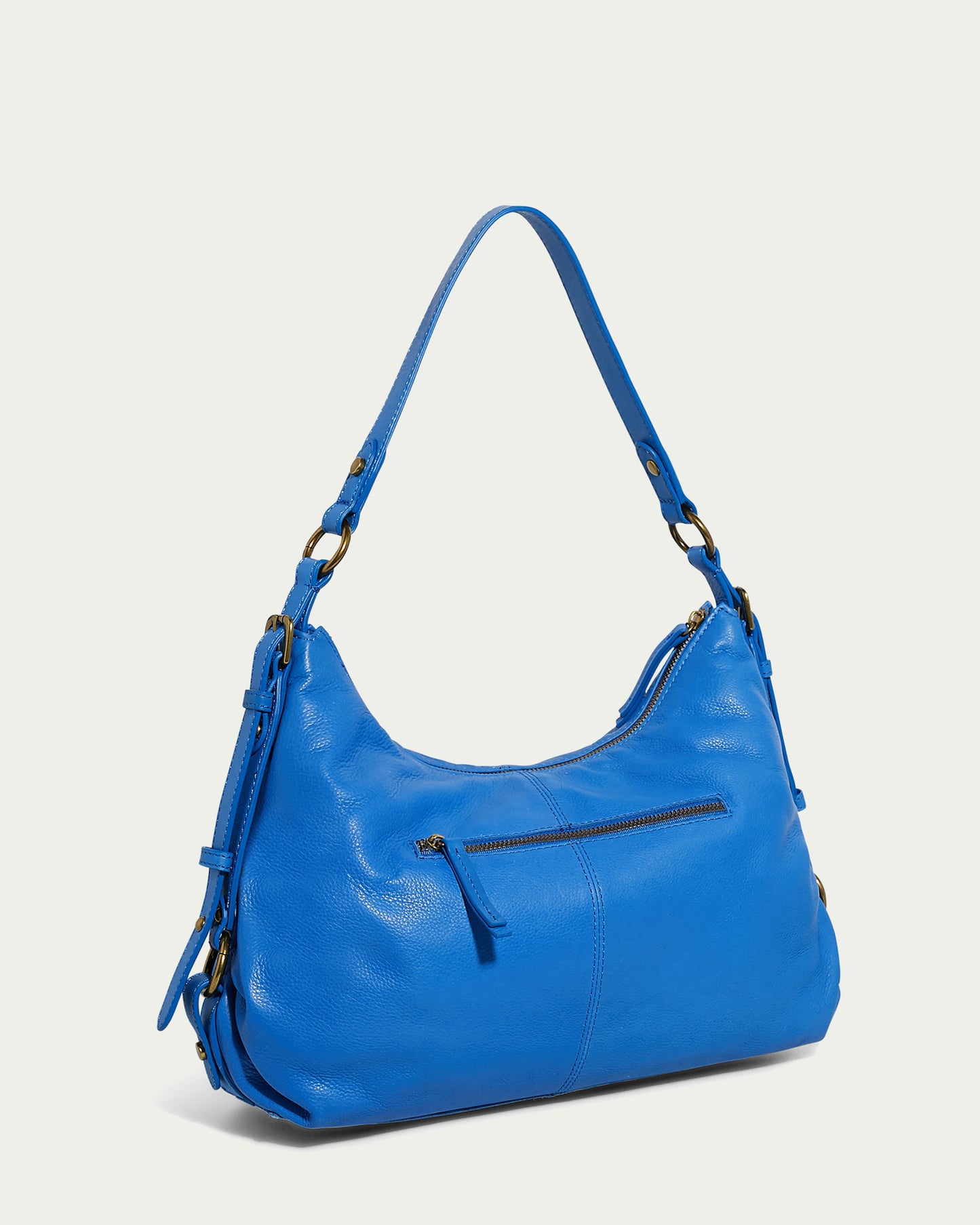 The Thayer Perfect Hobo by American Leather Co. is an eye-catching blue bag made from genuine leather, complete with a long shoulder strap and gold-tone hardware. Its design features a front zipper pocket and two side adjusters, all set against a subtle light background.