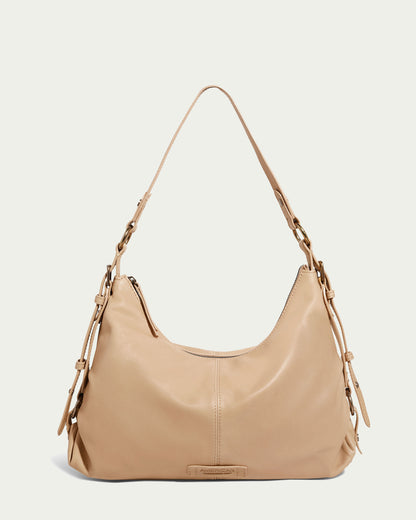 Introducing the Thayer Perfect Hobo from American Leather Co., a sophisticated beige leather purse featuring a single strap with buckle details. Crafted from genuine leather, this elegant bag showcases a curved top and a front logo patch, ensuring style and sophistication in every detail.