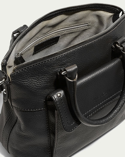 The Vona Convertible Dome Satchel by American Leather Co. is a black leather handbag with a textured finish and silver hardware. Crafted from genuine leather, this bag features two handles, a zippered main compartment, and an external pocket. Its interior is lined in light fabric and includes an inner zipper pocket along with an open pocket for organization.