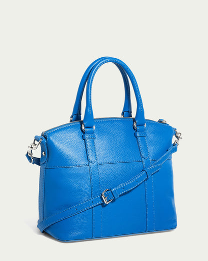 A vibrant blue Vona Convertible Dome Satchel by American Leather Co., equipped with dual handles and an optional shoulder strap. The bag is adorned with silver hardware, including a zipper and buckles. Made from genuine leather, it combines simplicity and elegance, making it perfect for both casual and formal settings.