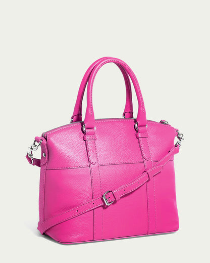 The Vona Convertible Dome Satchel from American Leather Co. is a vibrant pink genuine leather handbag with dual top handles and a detachable, adjustable shoulder strap. It boasts silver hardware, including a zipper closure and buckles. The exterior features a Forever Pebble textured finish with two vertical stitched lines for added detail.