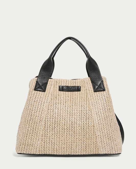 The Ada Triple Entry Satchel Raffia With Black by American Leather Co. is a beige woven handbag featuring black leather handles and trims, adorned with a subtle brand label on the front and soft texture, all set against a plain white background.