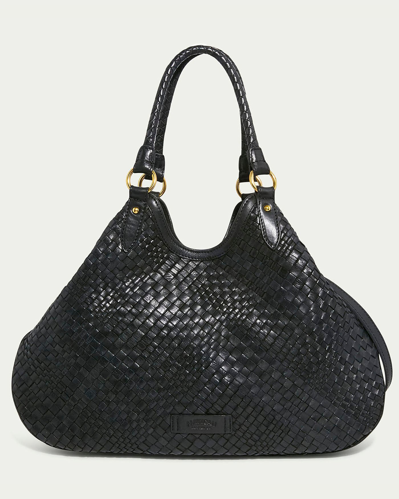 The Blair Convertible Tote by American Leather Co. is a spacious, structured woven leather bag in black. It features two handles with gold accents, a slightly curved top, and a small rectangular label on the front, making it versatile for any occasion.