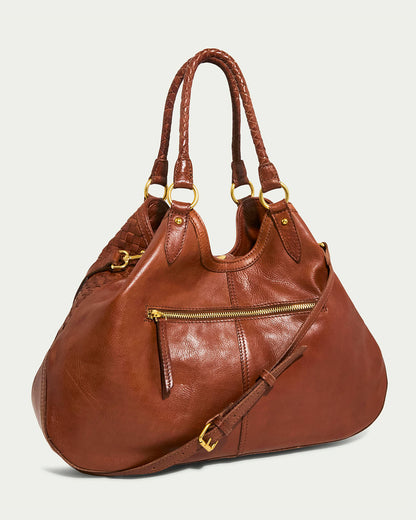 The Blair Convertible Tote by American Leather Co. is a chic, large brown woven leather handbag with multiple handles, including braided ones. It has a front zip pocket, detachable shoulder strap with gold buckle, and gold-tone hardware for versatile style.