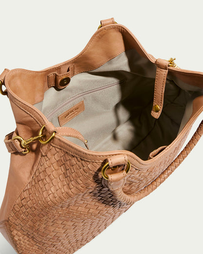 The Blair Convertible Tote by American Leather Co. features genuine woven leather, gold hardware, and a button closure. Its chic design includes an open beige interior with a small pocket, combining style and functionality for any occasion.