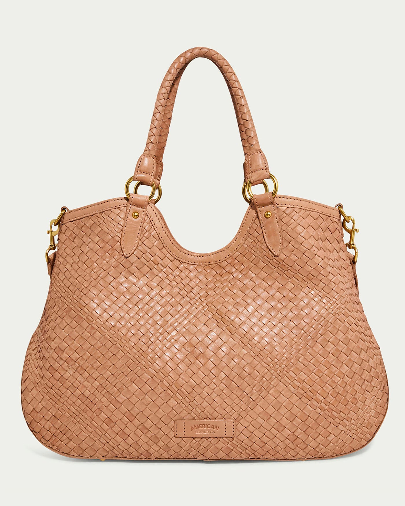 The Blair Convertible Tote from American Leather Co. is a chic tan leather handbag featuring two handles, gold-toned hardware, a woven diamond pattern, and a small rectangular front tag.