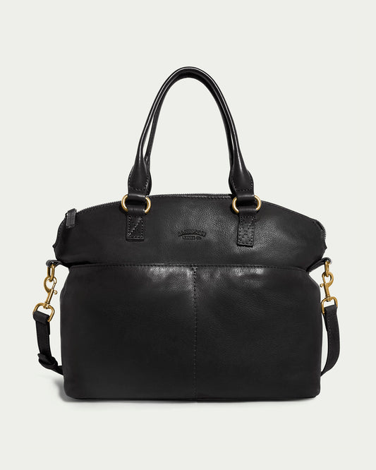 The Carrie Dome Satchel by American Leather Co. is a black leather bag with two short handles, an adjustable crossbody strap, and gold hardware. It features genuine American leather, a front pocket, and top zip closure.