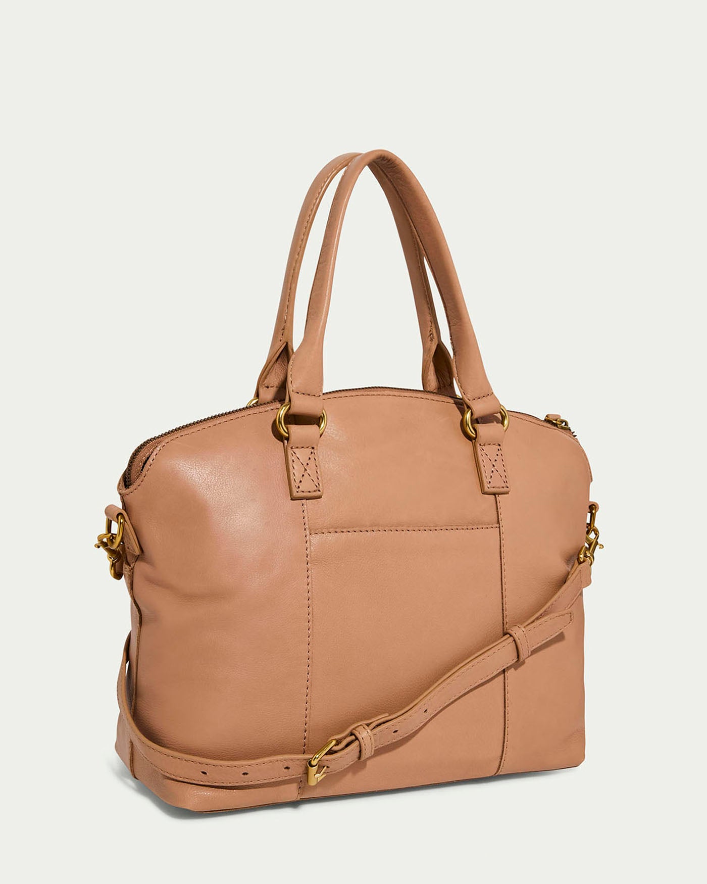 The Carrie Dome Satchel by American Leather Co. features a tan leather finish with dual handles and an adjustable crossbody strap. It has gold-tone hardware, a front pocket, a zip closure, and offers a structured rectangular shape with a smooth texture.