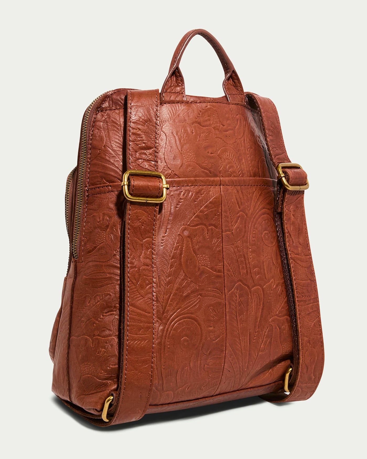 The Cleveland Backpack by American Leather Co. is a genuine leather purse with detailed embossed bird and foliage designs, featuring adjustable straps with antiqued brass buckles and a top handle. It's showcased on a light background, highlighting its back and side.