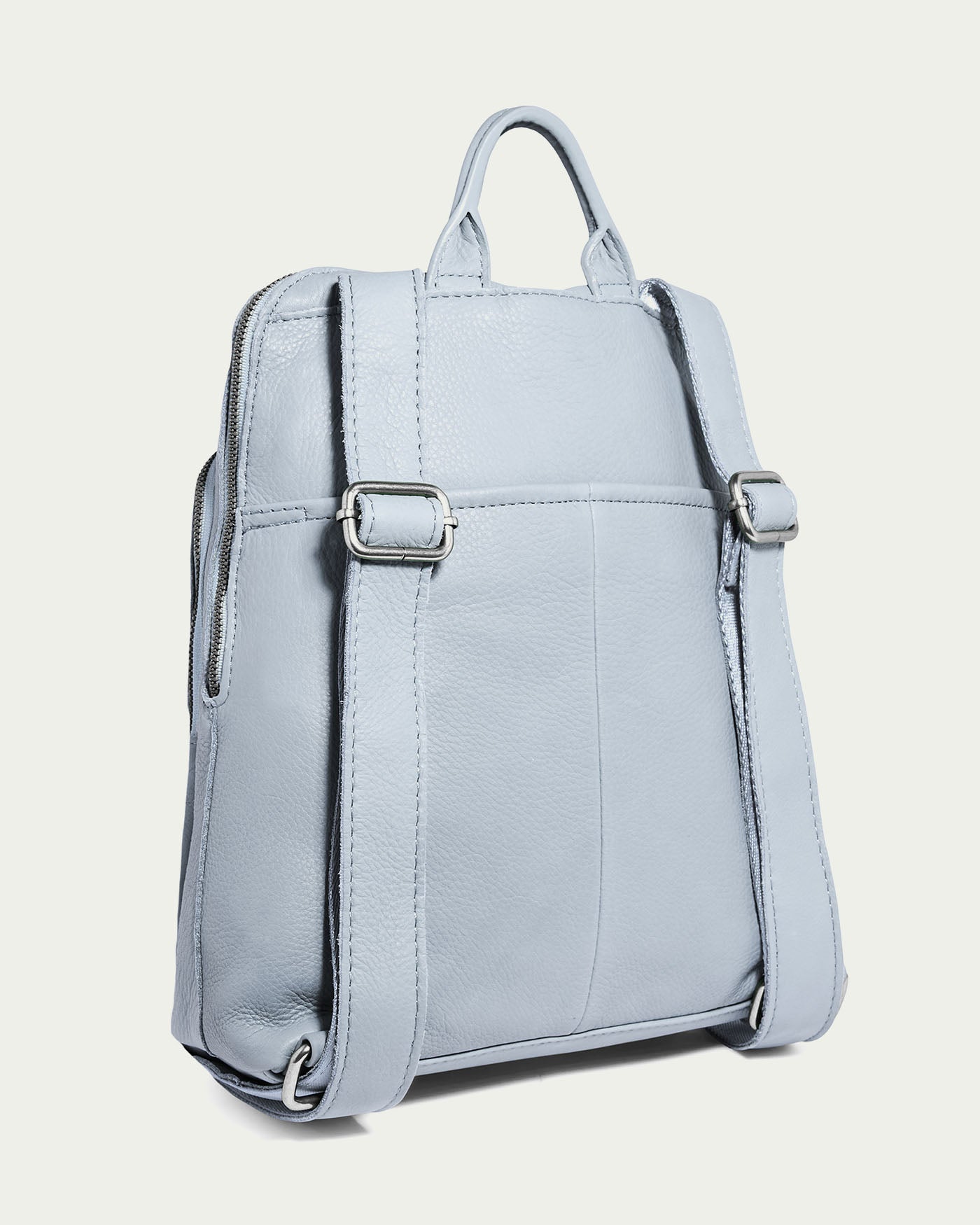 The Cleveland Backpack by American Leather Co. is a light blue leather bag featuring textured material with adjustable straps, metal buckles, a top handle, side zippers, and a sleek minimalist design, shown against a plain background.