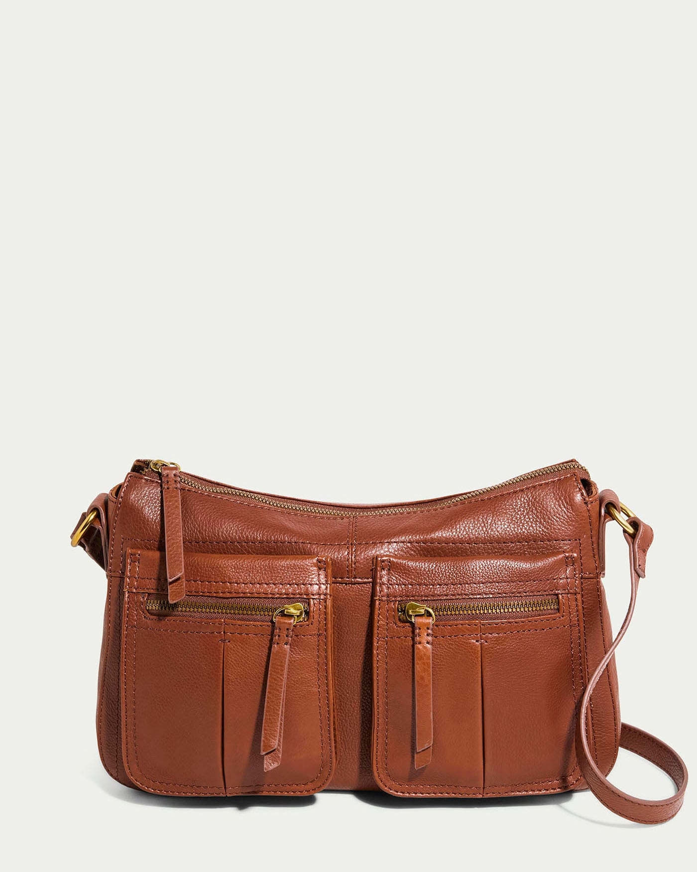 The Holton Crossbody by American Leather Co. is a brandy glove leather handbag with two front zippered pockets and a shoulder strap. Its spacious design features sleek gold-tone hardware, suitable for both casual and formal occasions.