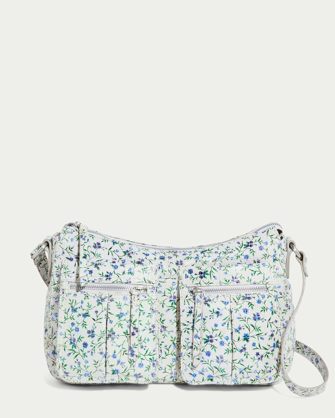 The Holton Crossbody by American Leather Co. in "Pleasantville" is a floral shoulder bag with a light background and blue-green details. It includes two front zip pockets and an adjustable strap, merging comfort and style elegantly.