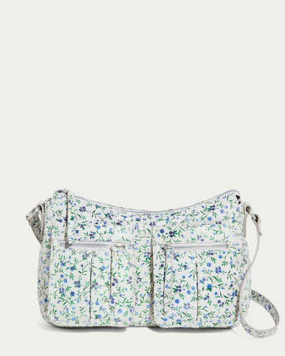 The Holton Crossbody by American Leather Co. in "Pleasantville" is a floral shoulder bag with a light background and blue-green details. It includes two front zip pockets and an adjustable strap, merging comfort and style elegantly.