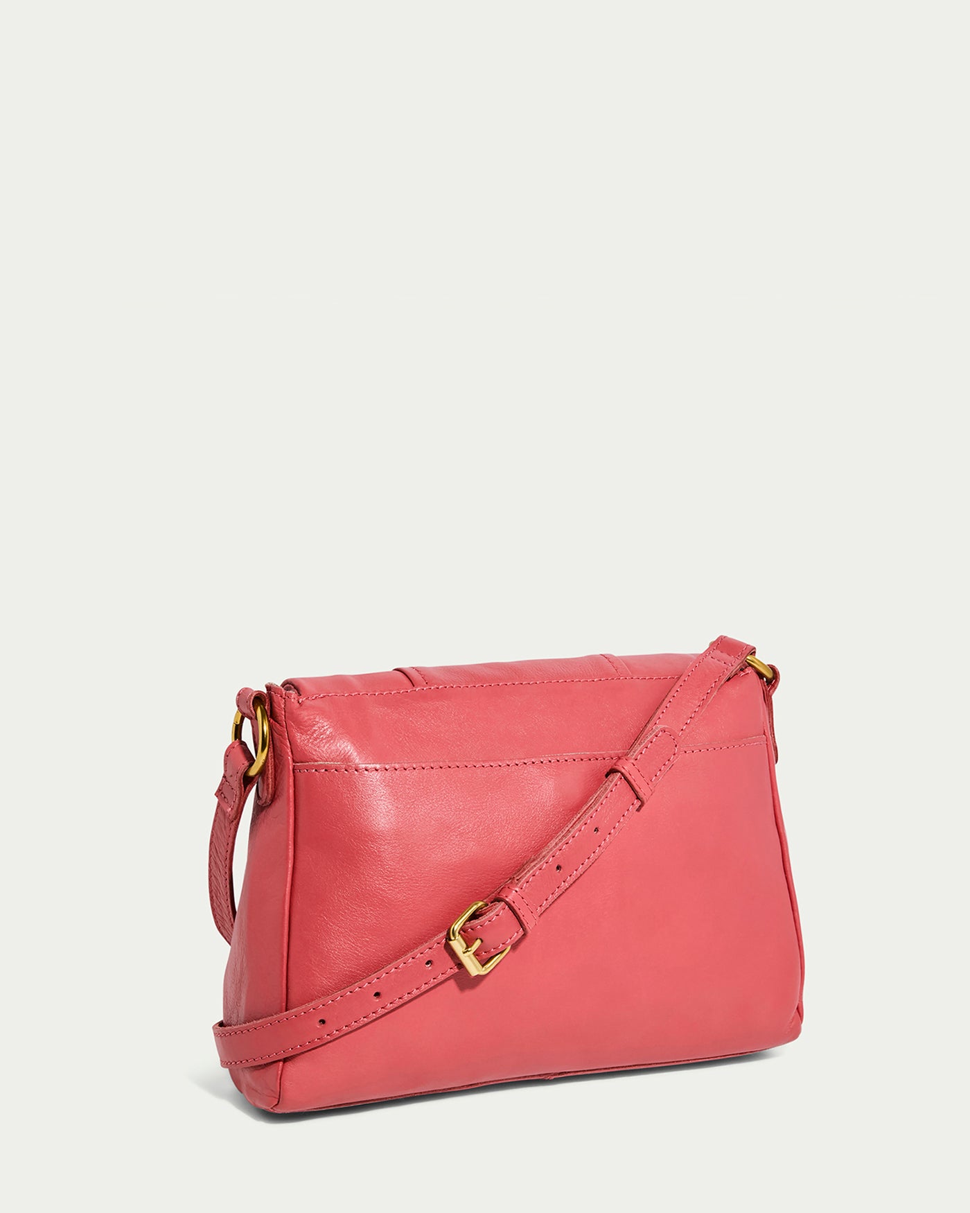 An American Leather Co. Lee Double Entry Crossbody in pink genuine leather, with a long adjustable strap and a brass buckle, set against a plain white background.