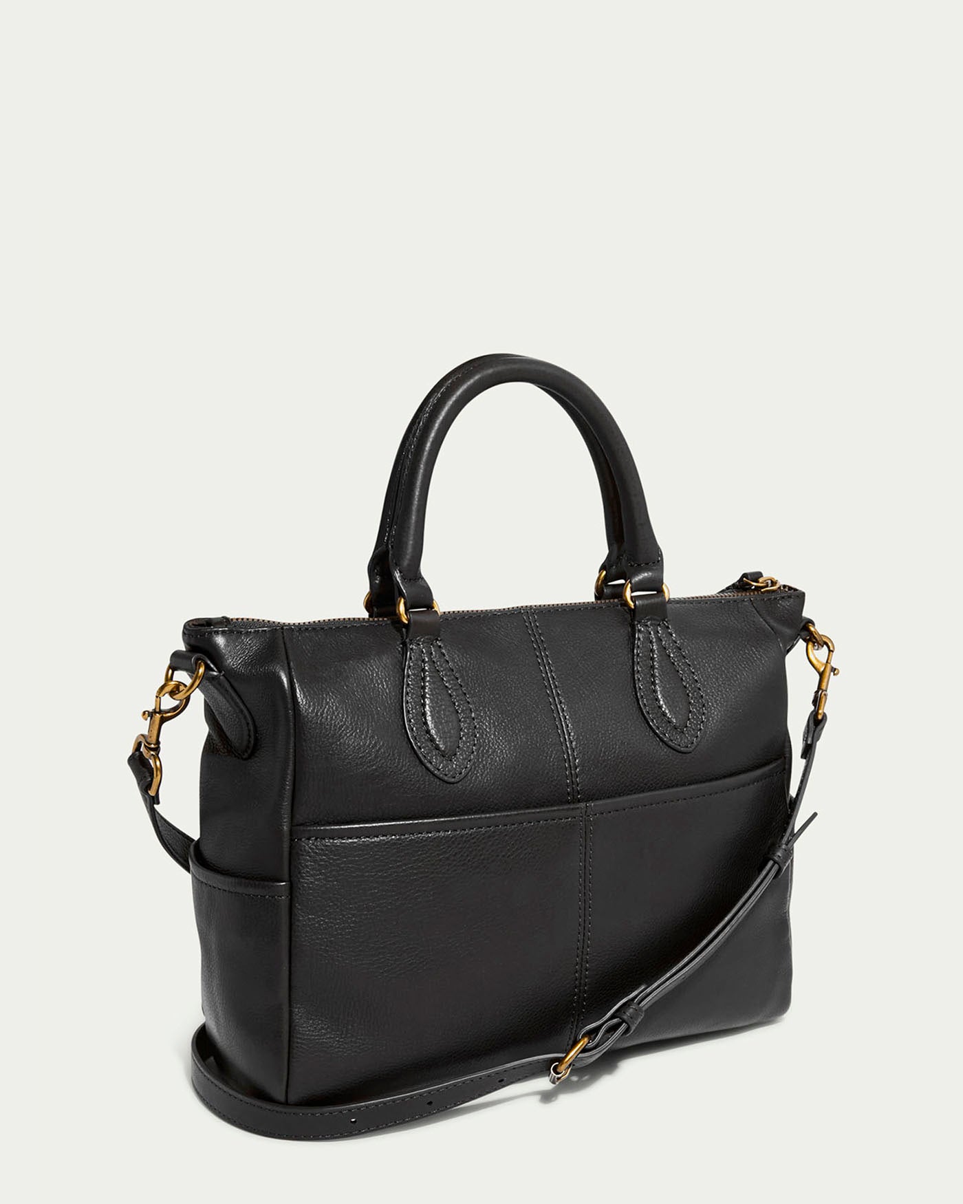 The Madison Satchel by American Leather Co. is made from luxurious black glove leather, featuring dual handles, a detachable shoulder strap, gold-tone hardware, and a top zip closure. Its structured shape with visible stitching stands out against a plain light background.