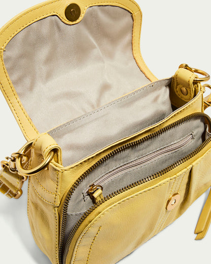 The American Leather Co. Marino Mini Crossbody is a small yellow glove leather shoulder bag with an open flap, magnetic closure, zippered compartment, and adjustable strap with metal hardware. It features a light beige fabric lining inside.