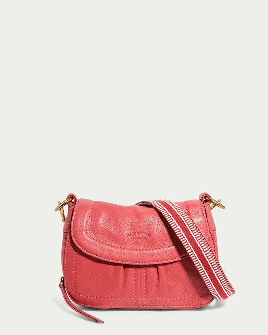 The Marino Mini Crossbody by American Leather Co. is a small French Rose glove leather bag with a flap closure, gold buckles on each side, and a pink and white striped adjustable strap. It features subtle brand embossing on the front flap.