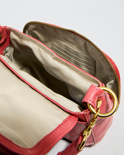 The Marino Mini Crossbody by American Leather Co. is an open pink glove leather handbag with a gold zipper and chain detail, featuring an adjustable strap. It has a beige-lined interior with empty pockets and card slots, set against a plain white background.