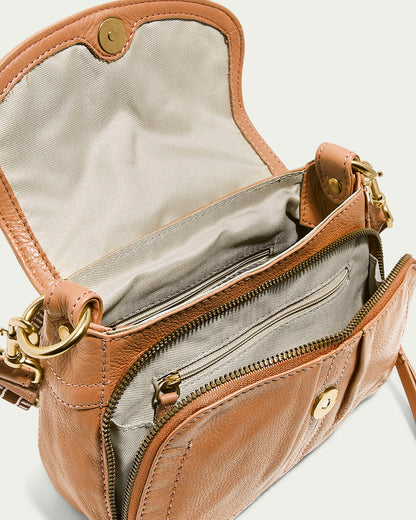 The Marino Mini Crossbody by American Leather Co. is a tan glove leather handbag with a gold button closure, unveiling a light gray fabric interior. It includes a front zippered pocket with a gold zipper and a shoulder strap attached via stylish gold rings.