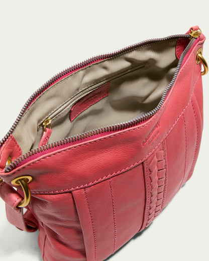 The Sherryl Crossbody by American Leather Co. is a pink glove leather handbag with intricate stitching and a top zipper, revealing a beige interior. It includes gold hardware, adjustable strap rings, and an embossed logo, blending elegance with functionality.