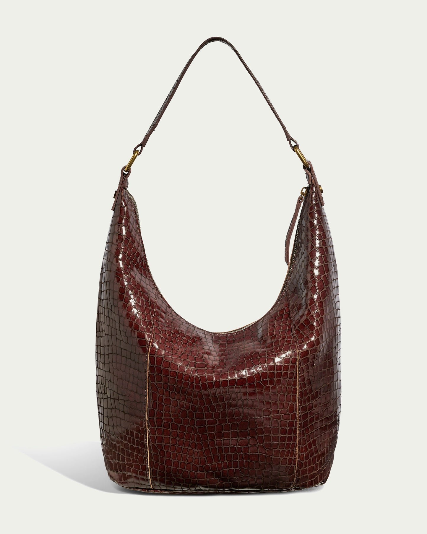 The Carrie Hobo by American Leather Co. is a brown, glossy handbag with a crocodile pattern, crafted from genuine American leather. It features a single strap and gold hardware, set against a plain light background.