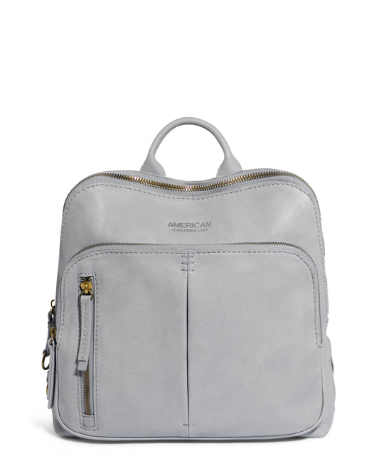 The Cleveland Midsize Backpack by American Leather Co. is a stylish gray leather bag with two zip compartments, a front zipper pocket, and a top handle. It features embossed branding on the front and elegant gold-tone hardware.