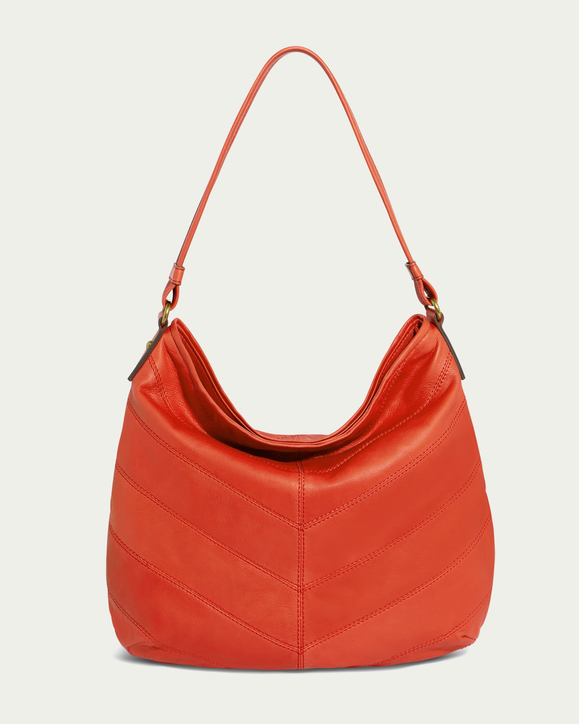 The Raleigh Ziptop Patchwork Hobo by American Leather Co. is highlighted on an off-white background; it boasts a striking orange genuine leather composition, a single strap, decorative stitching across the body, and a convenient zip top closure.