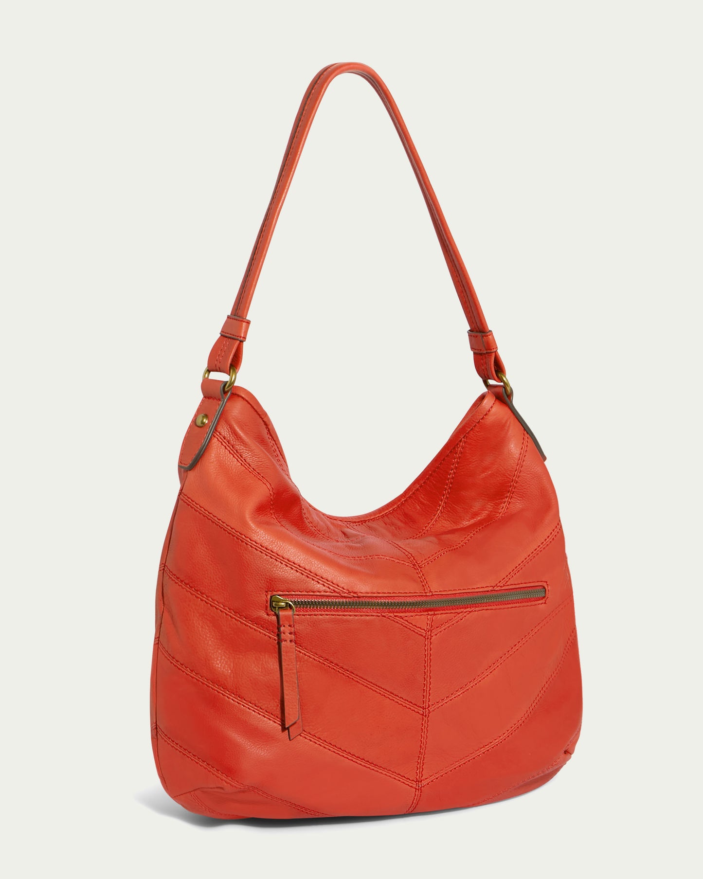 Introducing the Raleigh Ziptop Patchwork Hobo by American Leather Co.: a chic orange genuine leather bag with a curved silhouette and convenient shoulder strap. It showcases an eye-catching chevron patchwork design with a zigzag pattern, completed with a zip top closure, front zip pocket, and elegant brass hardware. The bag is beautifully displayed against a light background.