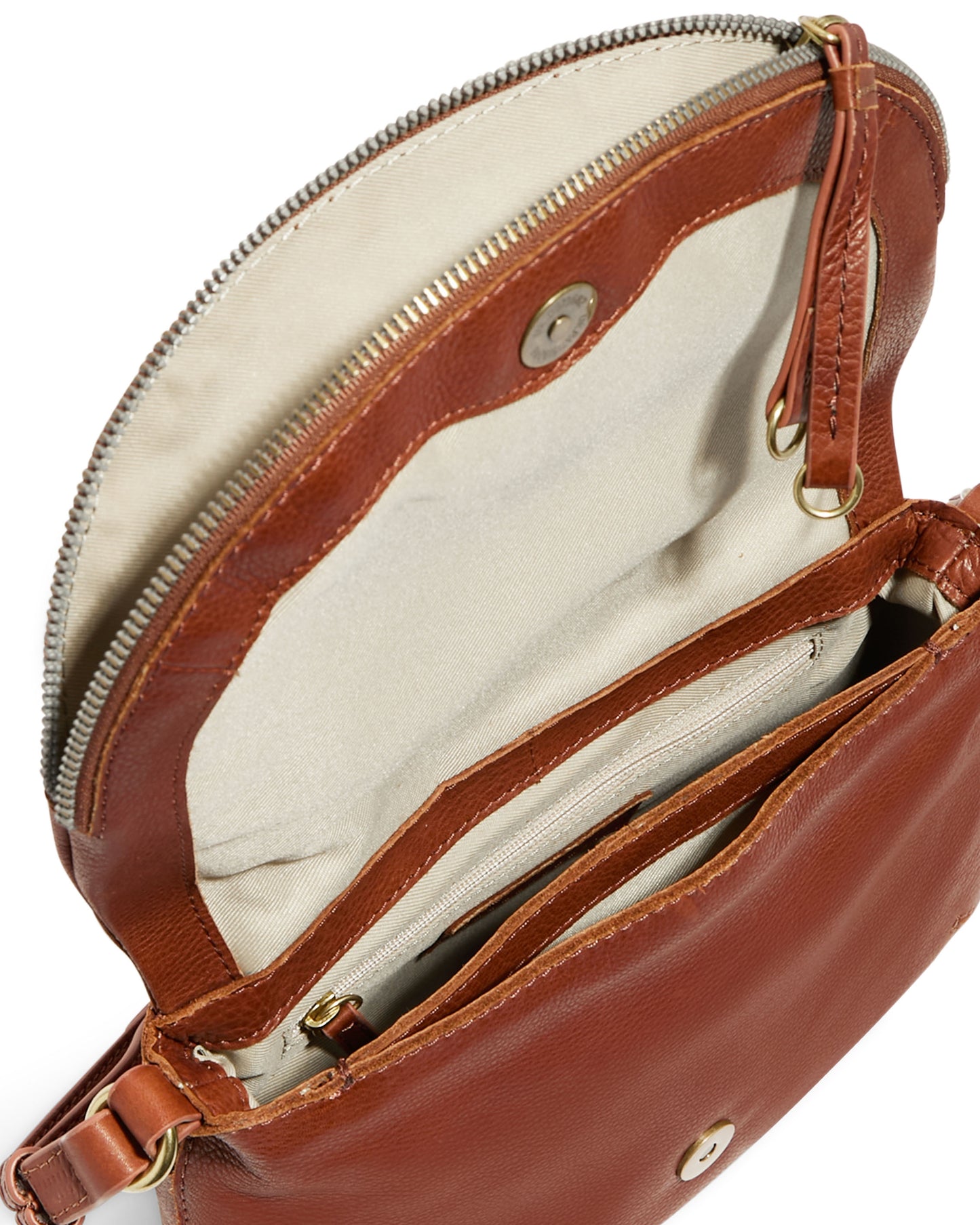 The Talya Double Entry Crossbody from American Leather Co. is an elegant bag crafted from genuine leather, featuring a zippered top and metal button closure. Its interior is lined with light beige fabric and showcases several compartments, including one with a zipper. A narrow adjustable leather strap with metal accents is also visible on the side.