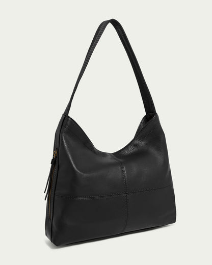 The Virginia Hobo by American Leather Co. is a sleek black leather bag with artisanal contrast stitching, a diagonal zipper pocket, and sturdy handles, all crafted from Genuine American Leather. It's showcased against a plain light background.