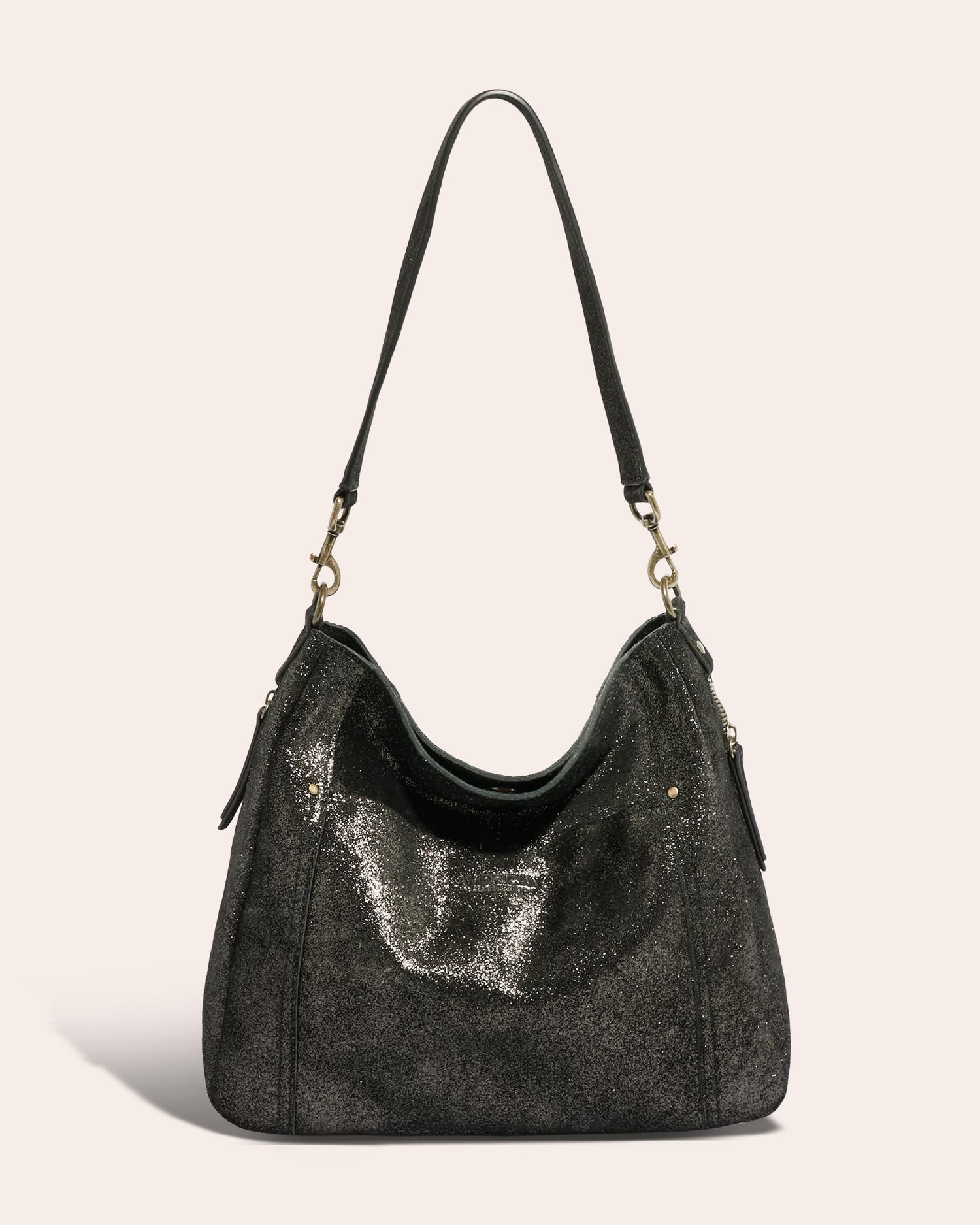 The Austin Shoulder by American Leather Co. is a glossy black hobo bag made of Genuine American Leather, featuring a short strap, gold hardware, and zippered side pockets. This stylish accessory boasts a slightly textured, shimmering surface and a slouchy, spacious design against a neutral background—making it the perfect casual addition to your wardrobe.