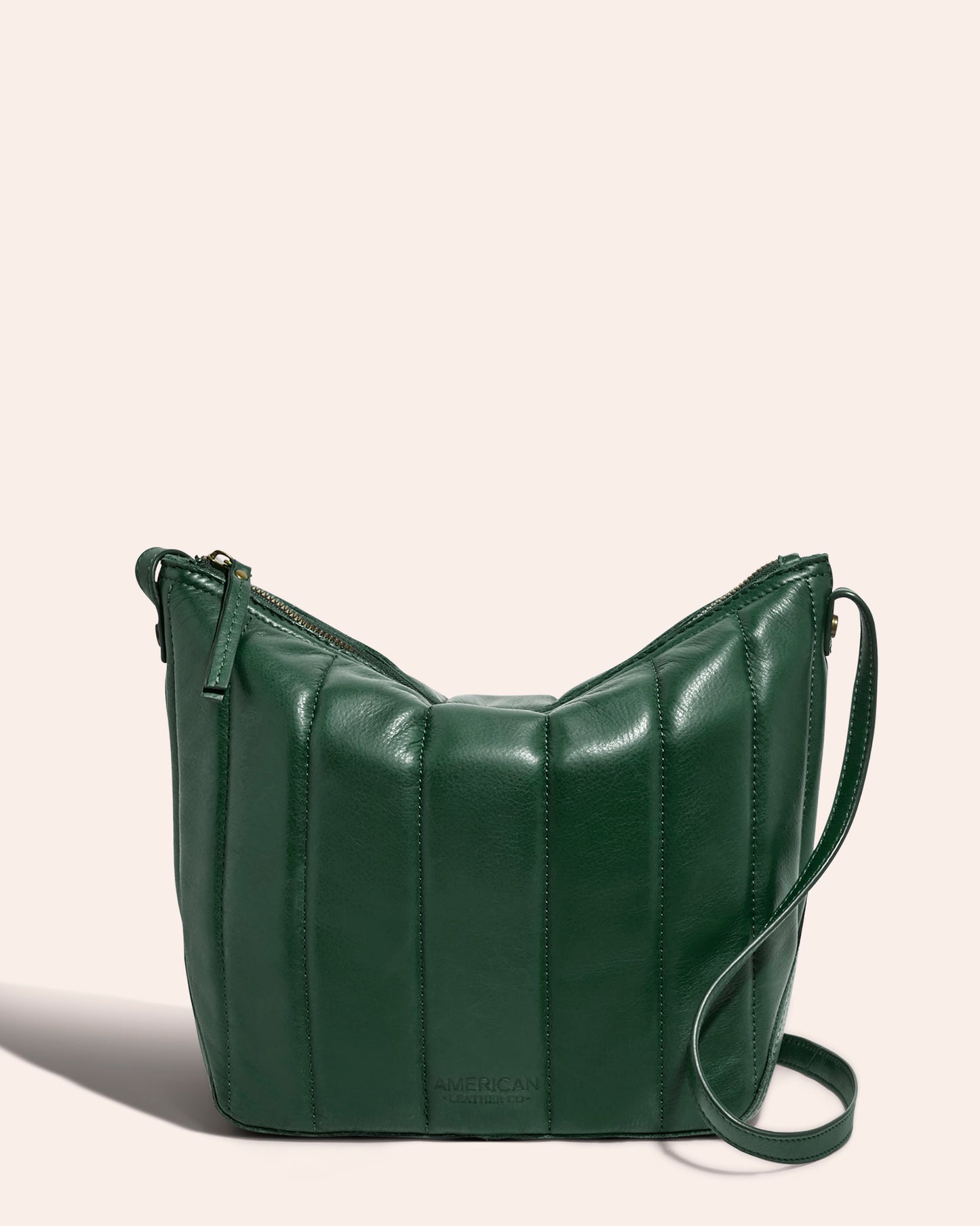 The Dayton Quilted Crossbody, crafted by American Leather Co., is a chic handbag in green made from buttery soft leather with a quilted design. It includes a zippered closure and an adjustable crossbody strap, all set against a neutral backdrop.