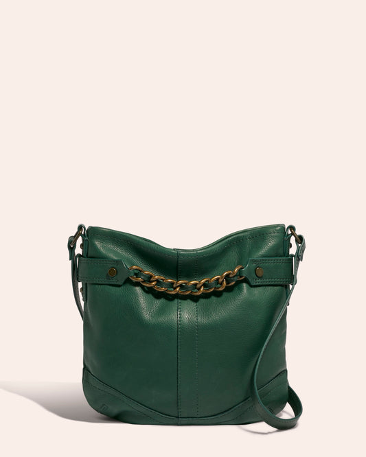 The Elton Crossbody by American Leather Co., a green leather handbag made from genuine American leather, features a gold chain detail and an adjustable crossbody strap, showcased against a plain beige background.