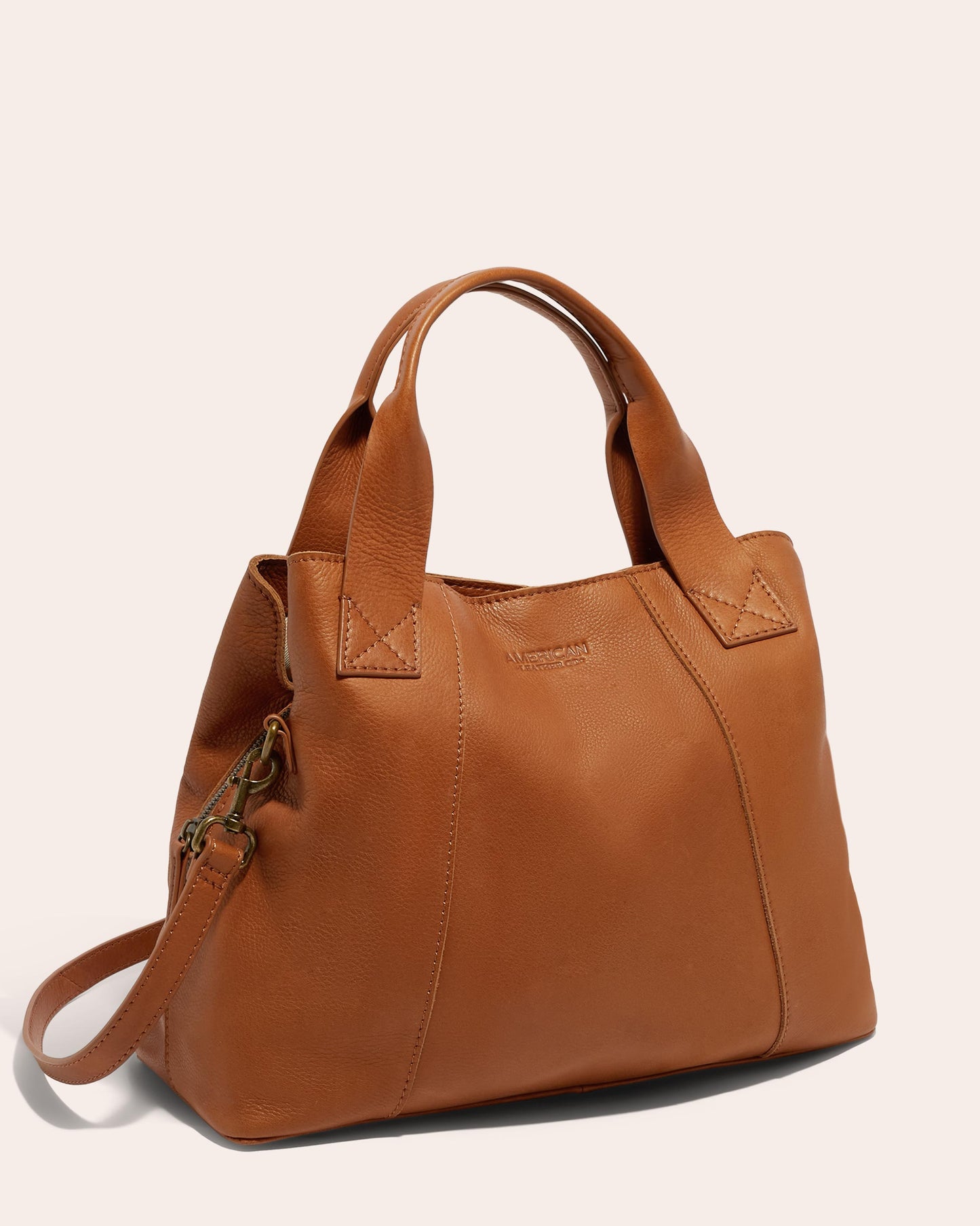 Introducing the Ada Triple Entry Satchel from American Leather Co. - a stylish brown leather handbag crafted from Genuine American Leather. It features dual handles, an adjustable crossbody strap, and a minimalist design with stitched accents and a spacious interior.