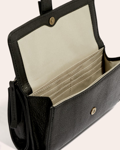 The Essex Wallet Crossbody by American Leather Co. is a stylish black purse crafted from genuine American leather. It features a flap opening that reveals multiple compartments and card slots, along with a light-colored fabric interior and snap button closure to enhance its design. The purse also includes an adjustable crossbody strap for versatile wear.